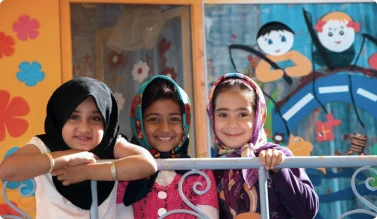 Three young students smiling at the AMCC Peace Academy