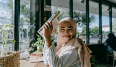 Smiling student holding a book at the AMCC Peace Academy