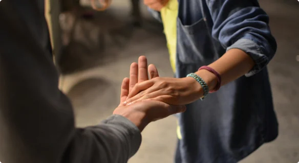 Two people clasping hands as one gives Zakat to another