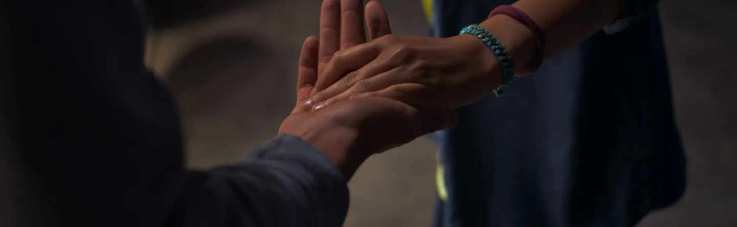 One hand gently placed in another, offering help